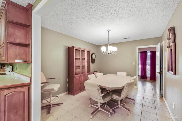 dining space featuring a textured ceiling, light tile patterned floors, and a chandelier