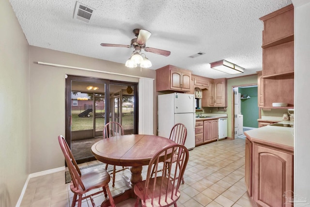 dining space with ceiling fan, sink, and a textured ceiling