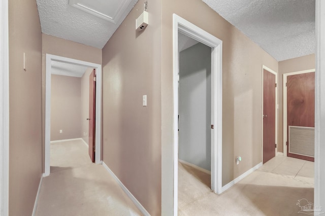 hall featuring light carpet and a textured ceiling