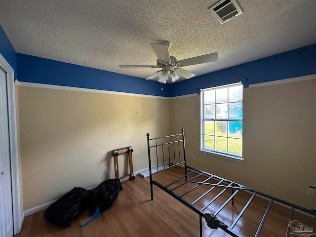 bedroom featuring a textured ceiling, ceiling fan, and hardwood / wood-style flooring