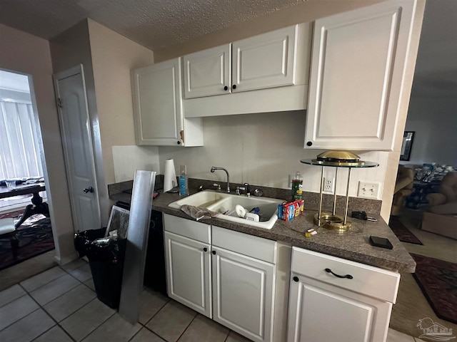 kitchen with white cabinets, a textured ceiling, light tile patterned floors, and sink