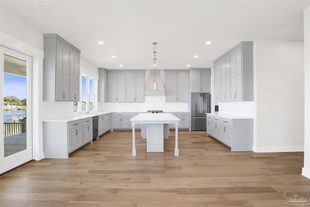 kitchen with stainless steel appliances, gray cabinets, light hardwood / wood-style floors, and a kitchen island