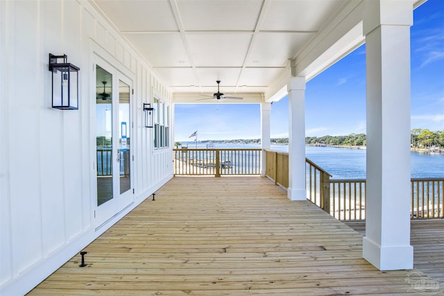 wooden terrace with a water view and ceiling fan