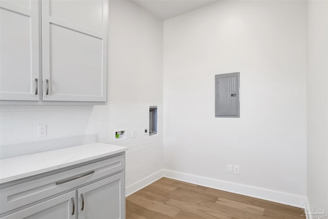 clothes washing area with electric panel, cabinets, washer hookup, hookup for an electric dryer, and light wood-type flooring