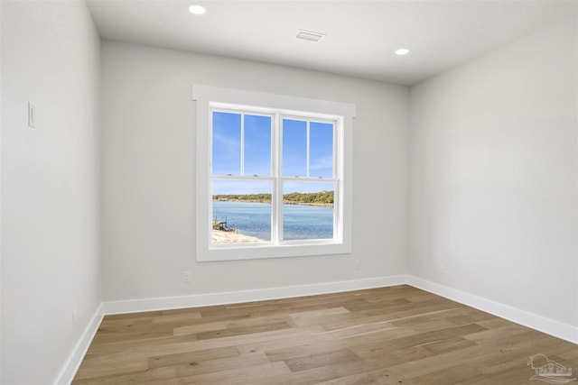 empty room featuring a water view and light wood-type flooring