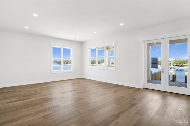 spare room with hardwood / wood-style flooring, a water view, and french doors