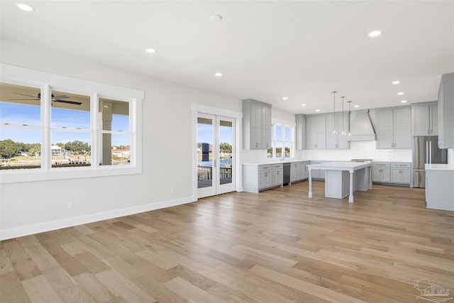 kitchen with premium range hood, gray cabinetry, hanging light fixtures, a kitchen breakfast bar, and a kitchen island