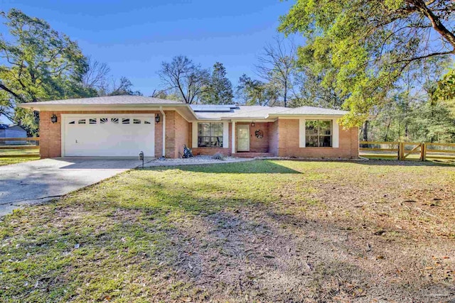 ranch-style house with a garage, concrete driveway, fence, roof mounted solar panels, and a front lawn