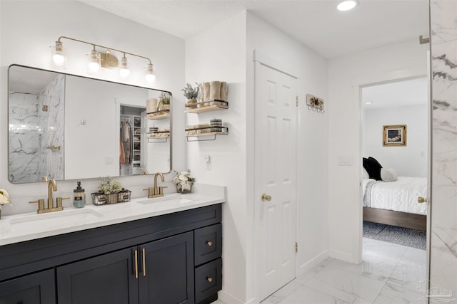 ensuite bathroom featuring double vanity, marble finish floor, a sink, and recessed lighting