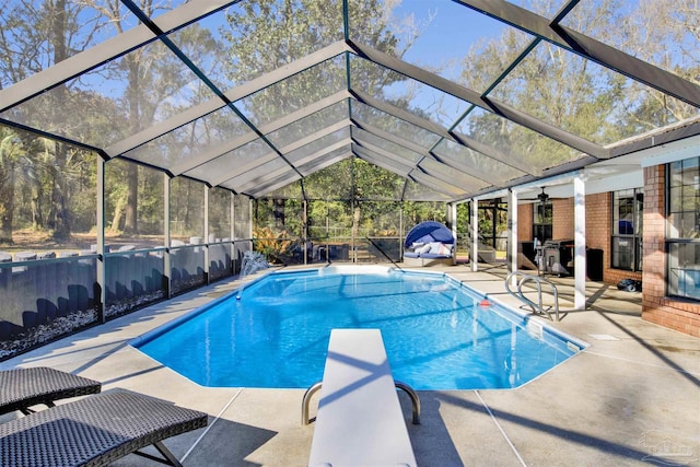 view of swimming pool featuring a fenced in pool, glass enclosure, ceiling fan, a patio area, and a diving board