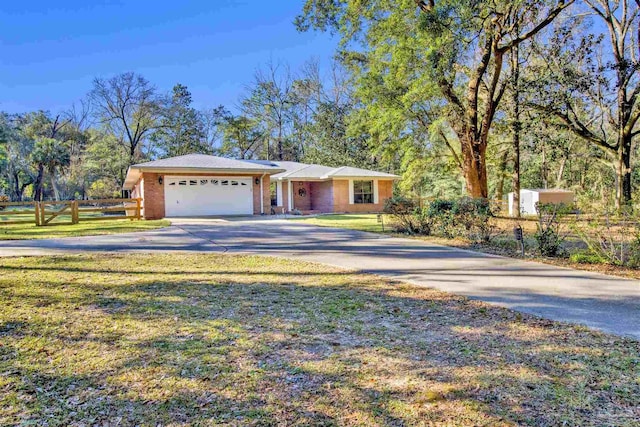 view of front facade featuring a garage, a front yard, driveway, and fence