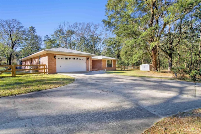 exterior space with a garage, brick siding, fence, driveway, and a yard