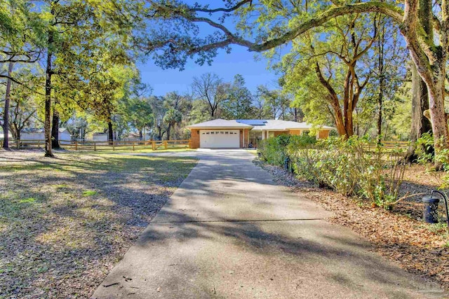 exterior space featuring a garage, driveway, fence, and solar panels