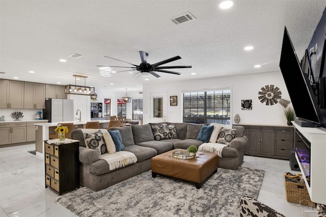 living room with marble finish floor, visible vents, a textured ceiling, and recessed lighting