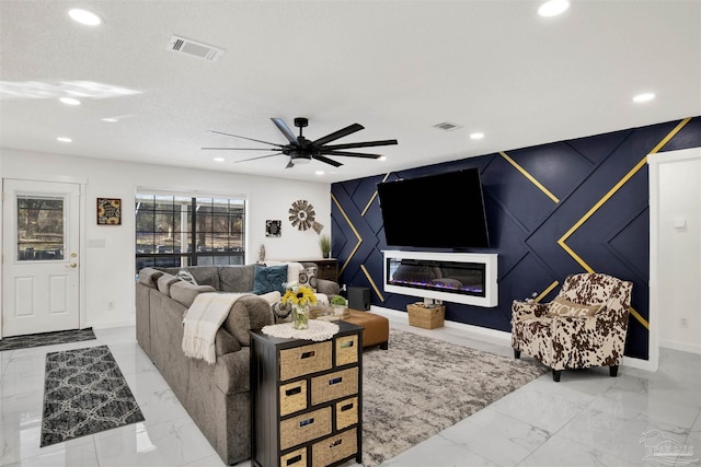 living room with marble finish floor, an accent wall, visible vents, and recessed lighting