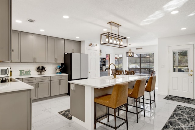 kitchen featuring a textured ceiling, a sink, marble finish floor, light countertops, and gray cabinets