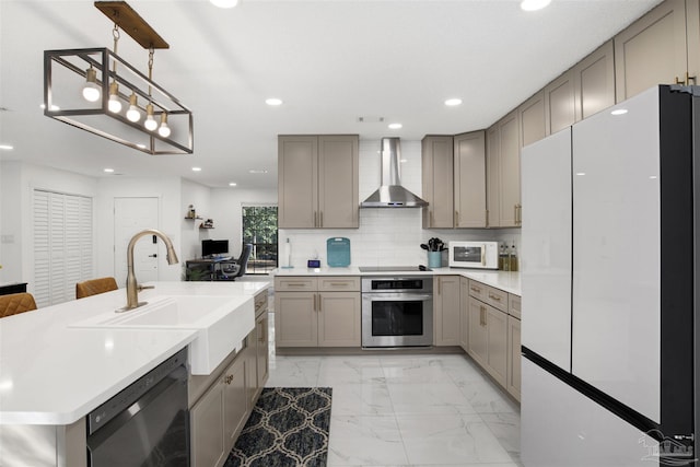 kitchen with gray cabinetry, stainless steel appliances, a sink, marble finish floor, and wall chimney range hood