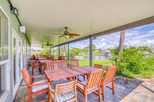 sunroom with a water view and ceiling fan