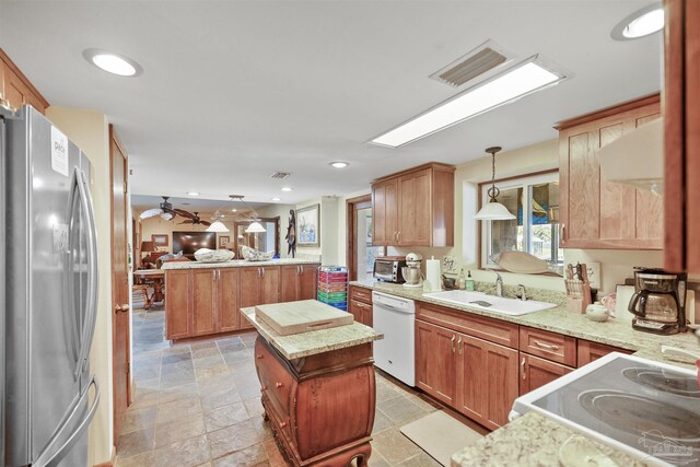 kitchen featuring stainless steel refrigerator, hanging light fixtures, white dishwasher, a kitchen island, and kitchen peninsula