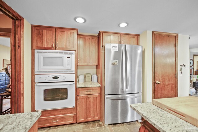 kitchen featuring white appliances and light stone countertops