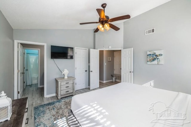 bedroom with vaulted ceiling, wood-type flooring, ceiling fan, and ensuite bath