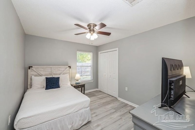 bedroom with ceiling fan, a closet, and light hardwood / wood-style flooring