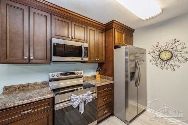 kitchen with dark stone counters and appliances with stainless steel finishes