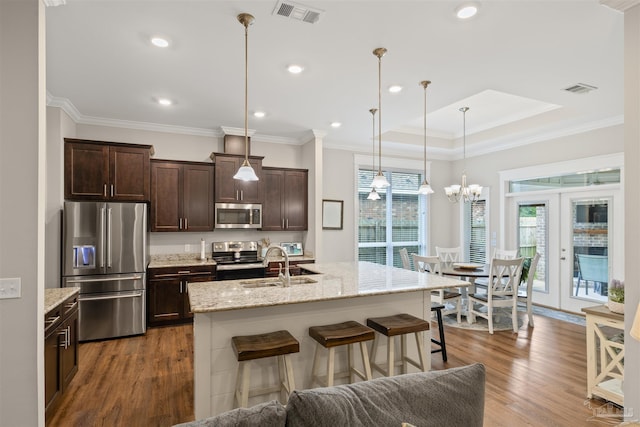 5622 Dunridge Dr, Pace, FL 32571 - kitchen featuring appliances with stainless steel finishes, dark brown cabinets, a breakfast bar, wood finished floors, and ornamental molding