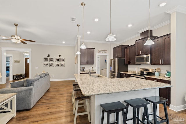5622 Dunridge Dr, Pace, FL 32571 - kitchen featuring stainless steel appliances, a breakfast bar area, open floor plan, dark brown cabinets, and a ceiling fan