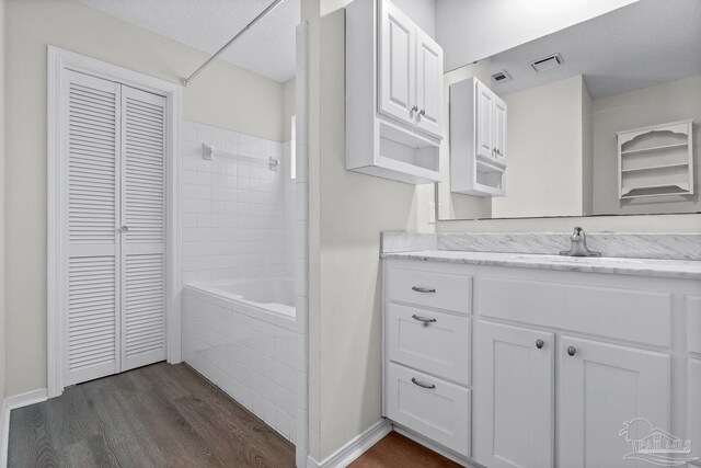 3514 Silvertree Ln, Pensacola, FL 32504 - bathroom featuring a closet, vanity, wood finished floors, tub / shower combination, and a textured ceiling