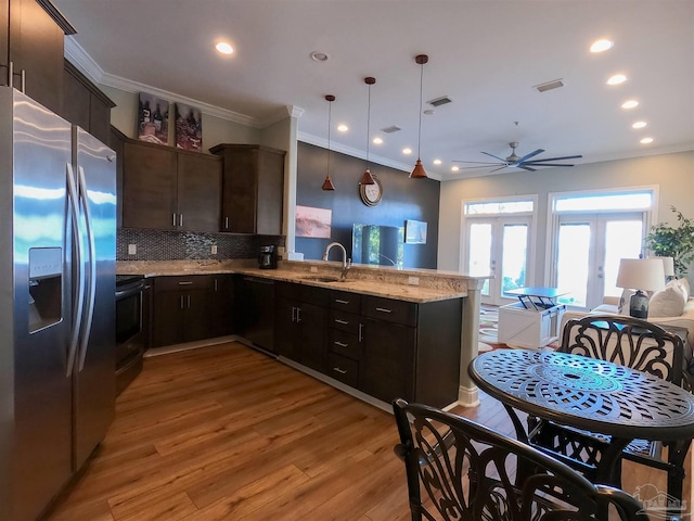 kitchen with kitchen peninsula, stainless steel refrigerator with ice dispenser, decorative backsplash, decorative light fixtures, and french doors