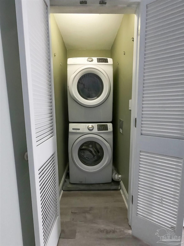 washroom featuring stacked washing maching and dryer and light hardwood / wood-style flooring