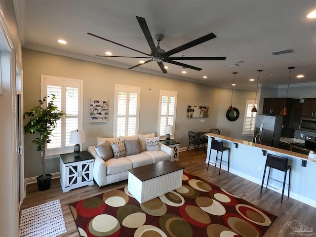 living room featuring ceiling fan, a healthy amount of sunlight, dark hardwood / wood-style floors, and crown molding