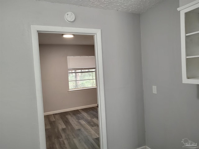 hallway with a textured ceiling and dark hardwood / wood-style flooring