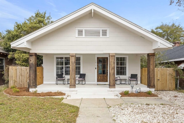 rear view of house featuring covered porch and fence