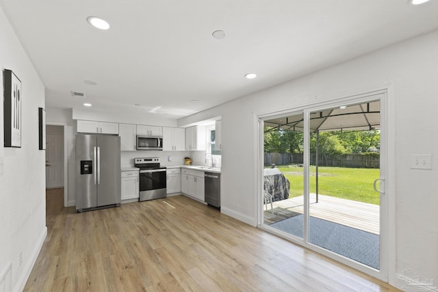 4224 Seaport Rd, Pace, FL 32571 - kitchen with stainless steel appliances, light wood-style flooring, light countertops, white cabinetry, and recessed lighting