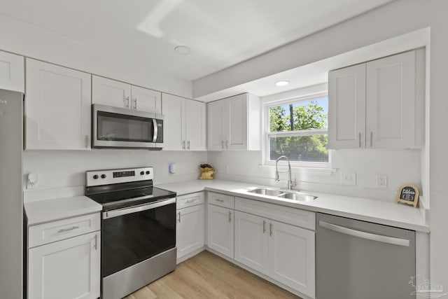 4224 Seaport Rd, Pace, FL 32571 - kitchen with appliances with stainless steel finishes, a sink, white cabinetry, light countertops, and light wood-style flooring