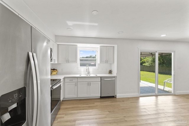 4224 Seaport Rd, Pace, FL 32571 - kitchen with appliances with stainless steel finishes, a sink, light wood-style flooring, light countertops, and white cabinets