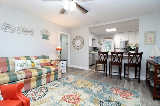 living room featuring ceiling fan and dark hardwood / wood-style floors