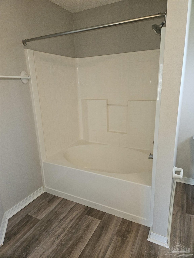 bathroom with baseboards, wood finished floors, and shower / bathtub combination