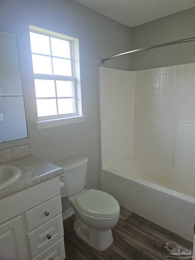 bathroom featuring toilet,  shower combination, wood finished floors, and vanity