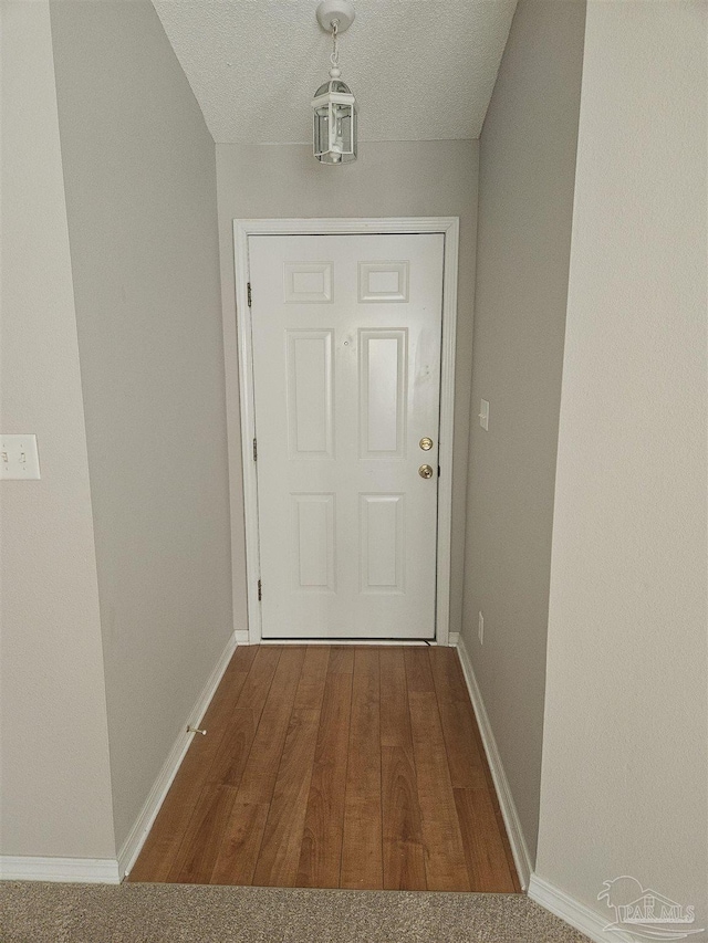 entryway with a textured ceiling, baseboards, and wood finished floors