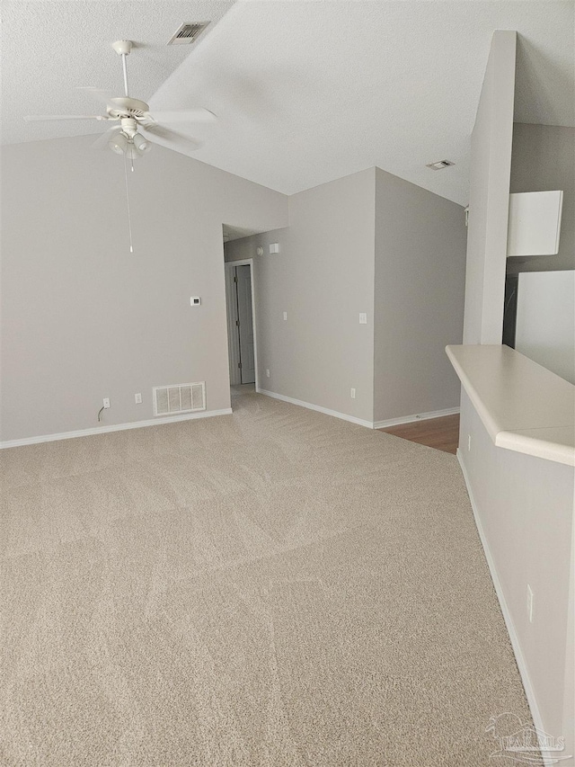 spare room with light carpet, a textured ceiling, visible vents, and baseboards