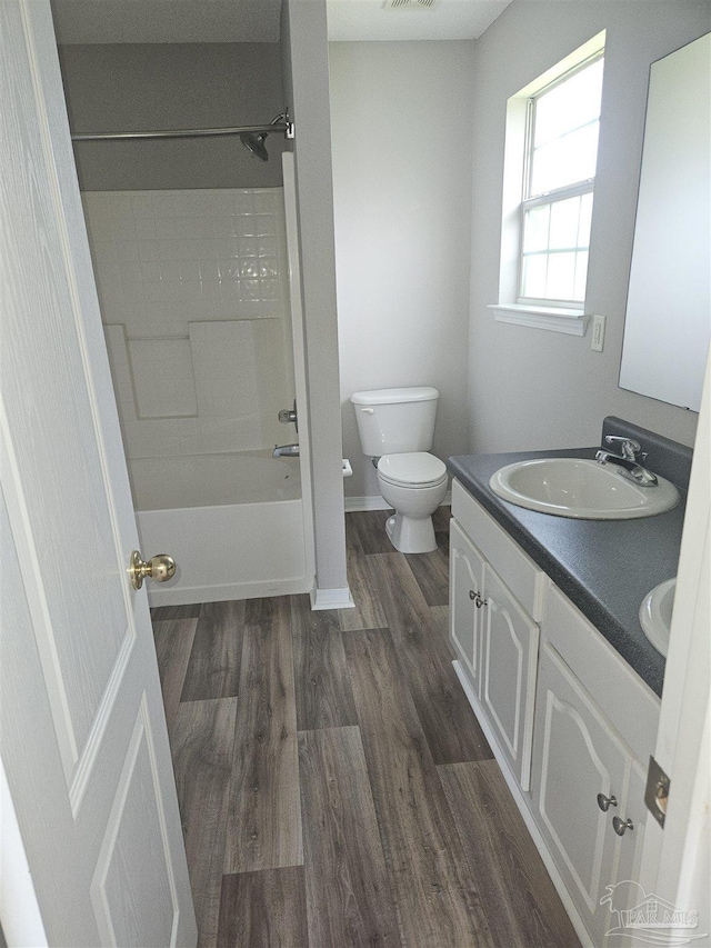 full bathroom featuring double vanity, toilet, a sink, wood finished floors, and  shower combination