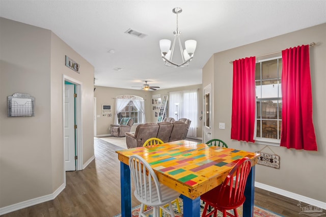 dining area with ceiling fan with notable chandelier and dark hardwood / wood-style flooring