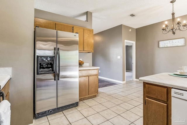 kitchen featuring an inviting chandelier, stainless steel fridge, light tile patterned flooring, white dishwasher, and pendant lighting