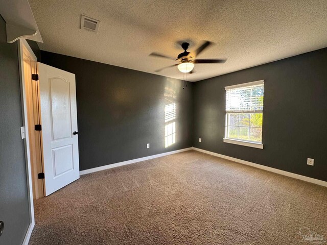 carpeted spare room featuring a textured ceiling and ceiling fan