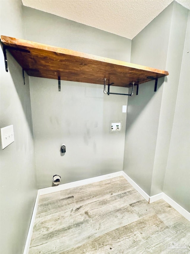 washroom with light hardwood / wood-style floors, hookup for a washing machine, and a textured ceiling