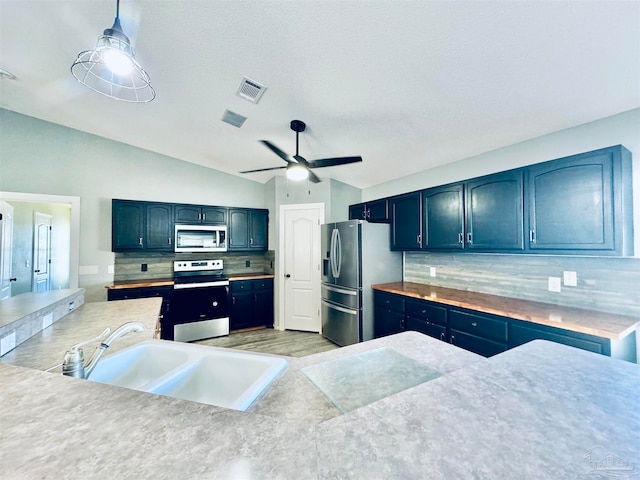 kitchen featuring sink, decorative light fixtures, ceiling fan, tasteful backsplash, and appliances with stainless steel finishes