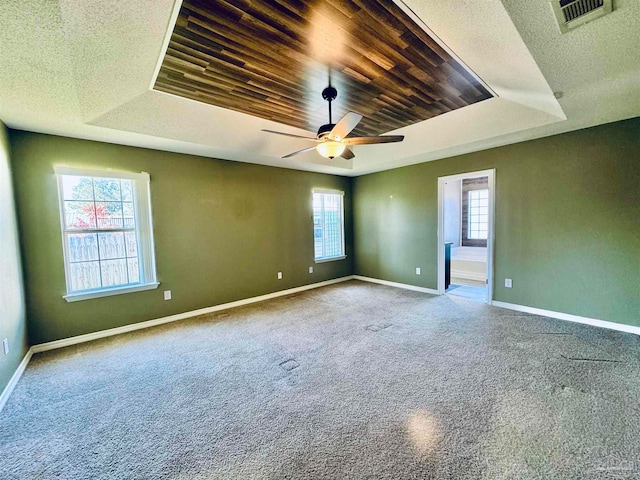 spare room with a raised ceiling, carpet floors, ceiling fan, and wooden ceiling